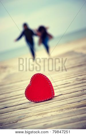 Red heart on the road with man and woman on the background