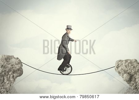 Brave business man riding an mono cycle between cliffs concept