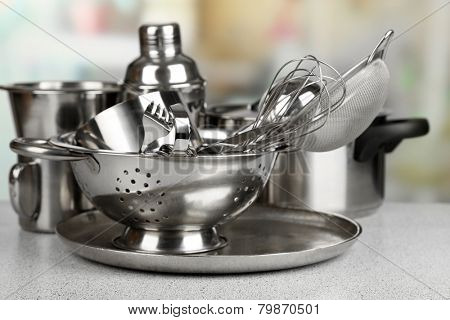 Stainless steel kitchenware on table, on light background