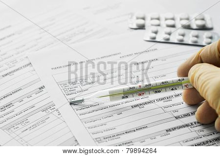 Thermometer In Man Hand On Patient Registration Form