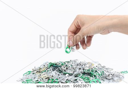 Hand Holding Aluminum Cap Can Over A Pile Of Cap Can