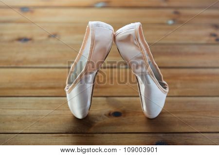 ballet, footwear and objects concept - close up of pointe shoes on wooden floor