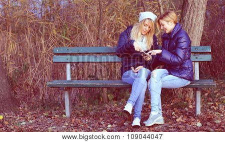 Young woman sitting on bench with her best friend