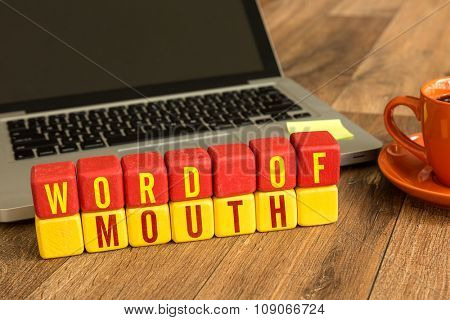 Word of Mouth written on a wooden cube in a office desk