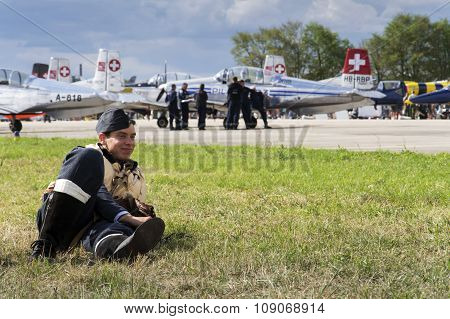Man In Vintage Pilot Uniform Smiling With The Swiss Pilatus Aerobatic Team P3 Flyers In Background