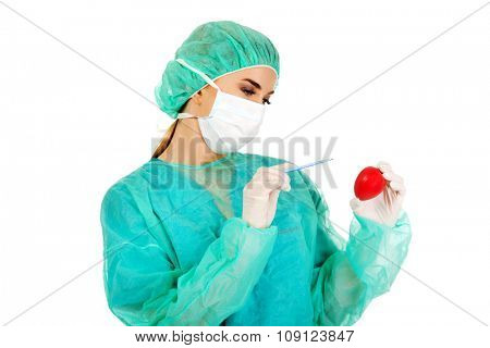 Young female cardiologist surgeron holding heart and scalpel.