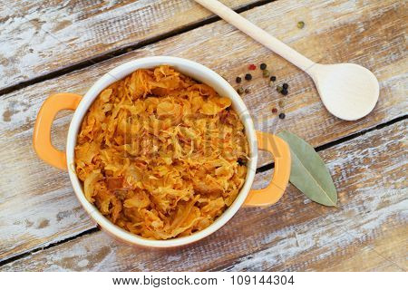 Polish bigos in saucepan on rustic wooden surface