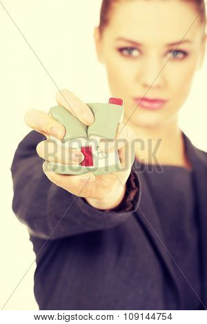 Aggresive businesswoman crushing small house.