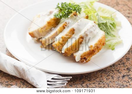 Sliced chicken cordon bleu with creamy sauce and romane leaf salad
