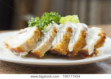 Sliced chicken cordon bleu with creamy sauce and romane leaf salad