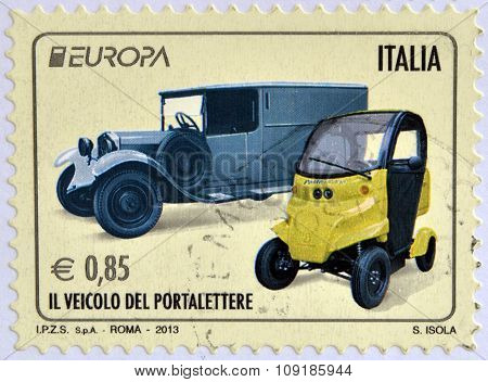 Stamp printed in Italy shows an old post car and a contemporary hybrid driven vehicle