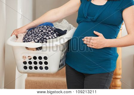 Close Up Of Pregnant Woman Doing Laundry At Home