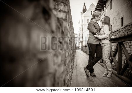 Young couple standing, kiss smb's lips,  on streets of old european city, vintage color