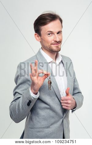 Portrait of a happy businessman showing ok sign and thumb up isolated on a white background