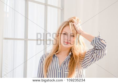 Portrait of relaxed pretty young woman with tousled hair in striped pajamas