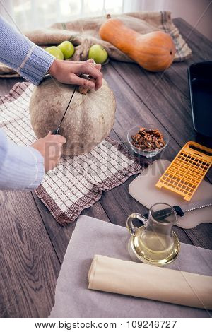Woman in kitchen making prepares a pie with pumpkin, selective focus