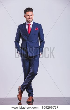 young man in suit posing with legs crossed while having hands in pockets
