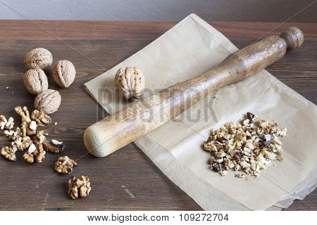 Walnuts in paper and wood battledore on a wooden background