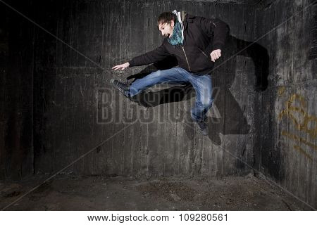 Man jumping in old black grungy room corner with shadows - breakdance concept