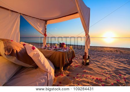 Romantic luxury dinner setting at tropical beach on sunset