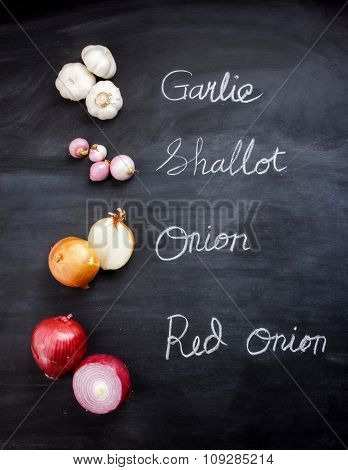 Garlic, Shallot, Onion, And Red Onion On Black Board
