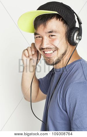 young asian man in hat and headphones listening music on white background