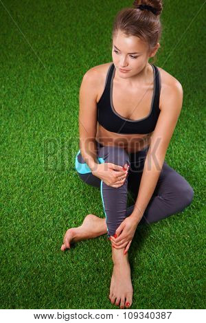 Beautiful young woman relaxing after exerscises on the grass 