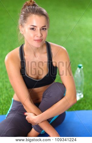 Beautiful young woman relaxing after exerscises on the grass 