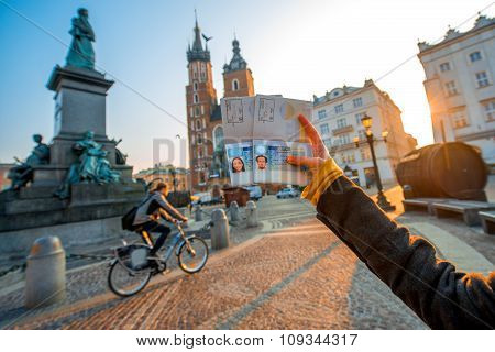 Female hands holding Ukrainian passports with Shengen visas on the Krakow city center background