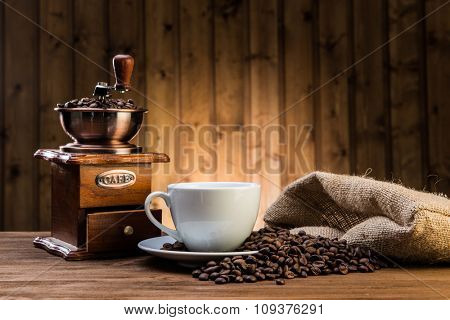 still life with coffee beans and old coffee mill on the wooden background 