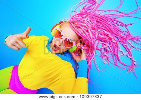 Ultra trendy DJ party girl in bright clothes, headphones and with bright dreadlocks. Disco, party. Show business. Bright fashion.