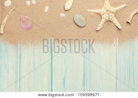 Sea sand with starfish and shells on wooden table. Top view with copy space. Toned