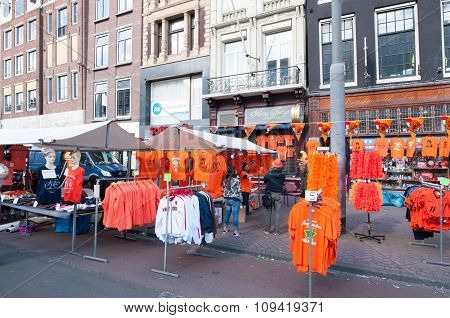 AMSTERDAM-APRIL 27, 2015: Locals display their goods for sale in traditional orange colour on Rokin during the King's Day in Amsterdam. Rokin is a major street in Amsterdam the Netherlands.