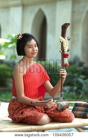 Thai Girl In Traditional Dress In Playing Thai Fiddle.