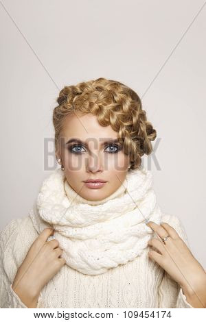 portrait of a beautiful young blonde woman on a light background. hair tied in a braid. girl wearing