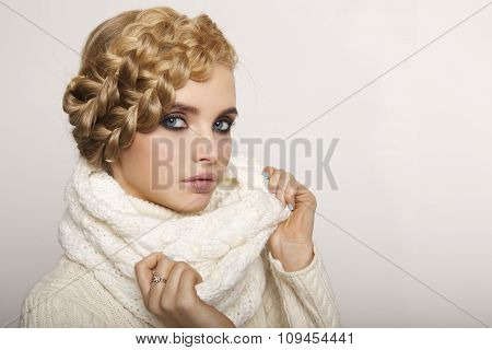 portrait of a beautiful young blonde woman on a light background. hair tied in a braid. girl wearing
