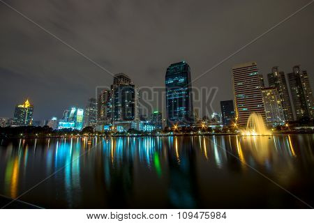 Golden reflection light in lake and Night view of Bangkok downtown at Benja kitti park, Thailand.