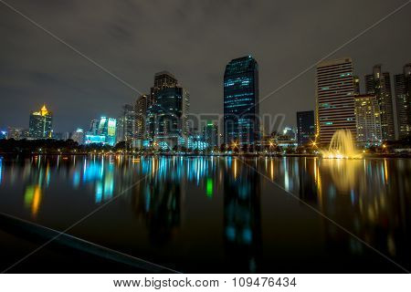 Golden reflection light in lake and Night view of Bangkok downtown at Benja kitti park, Thailand.