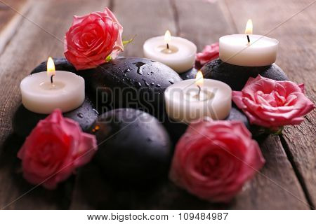 Tenderness relaxing composition with pebbles, roses and candles on wooden background, close up