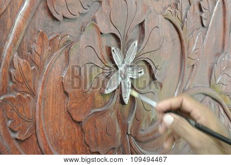 Skilled craftsman adding gold leaf skin to the wood carving