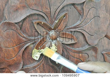Skilled craftsman adding gold leaf skin to the wood carving