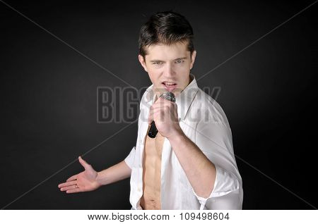 Expressively Man Singing With Microphone On Dark Background.