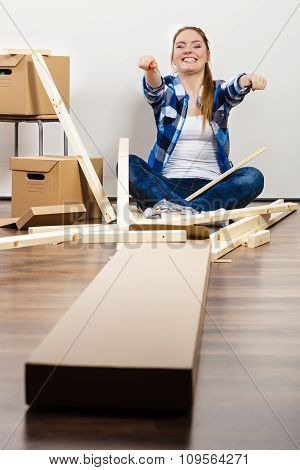 Woman Moving Into Apartment Assembly Furniture.