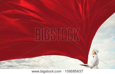 Young woman in white hat with opened red book in hands