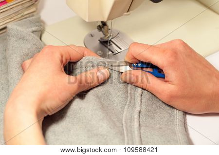 Woman's Hands With Scissors Cut The Thread After Sewing On The Sewing Machine