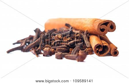 Two Cinnamon Sticks And A Pile Of Dried Cloves Cloves On A White Background