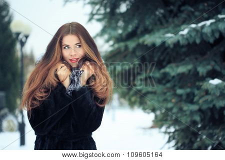 beautiful smiling girl on background of snowy trees. Winter portrait. coat with a hood
