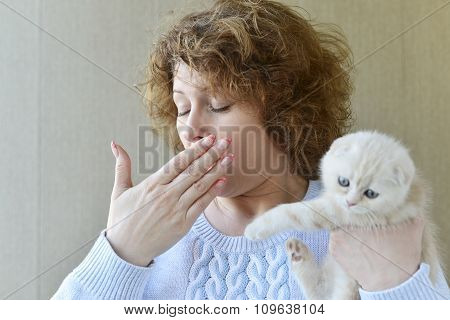 woman with allergy is holding  kitten