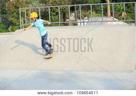 young woman skateboarder skateboarding at skatepark