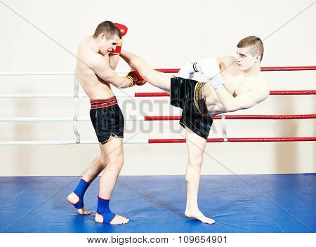 Two male muay thai boxers fighting at training boxing ring